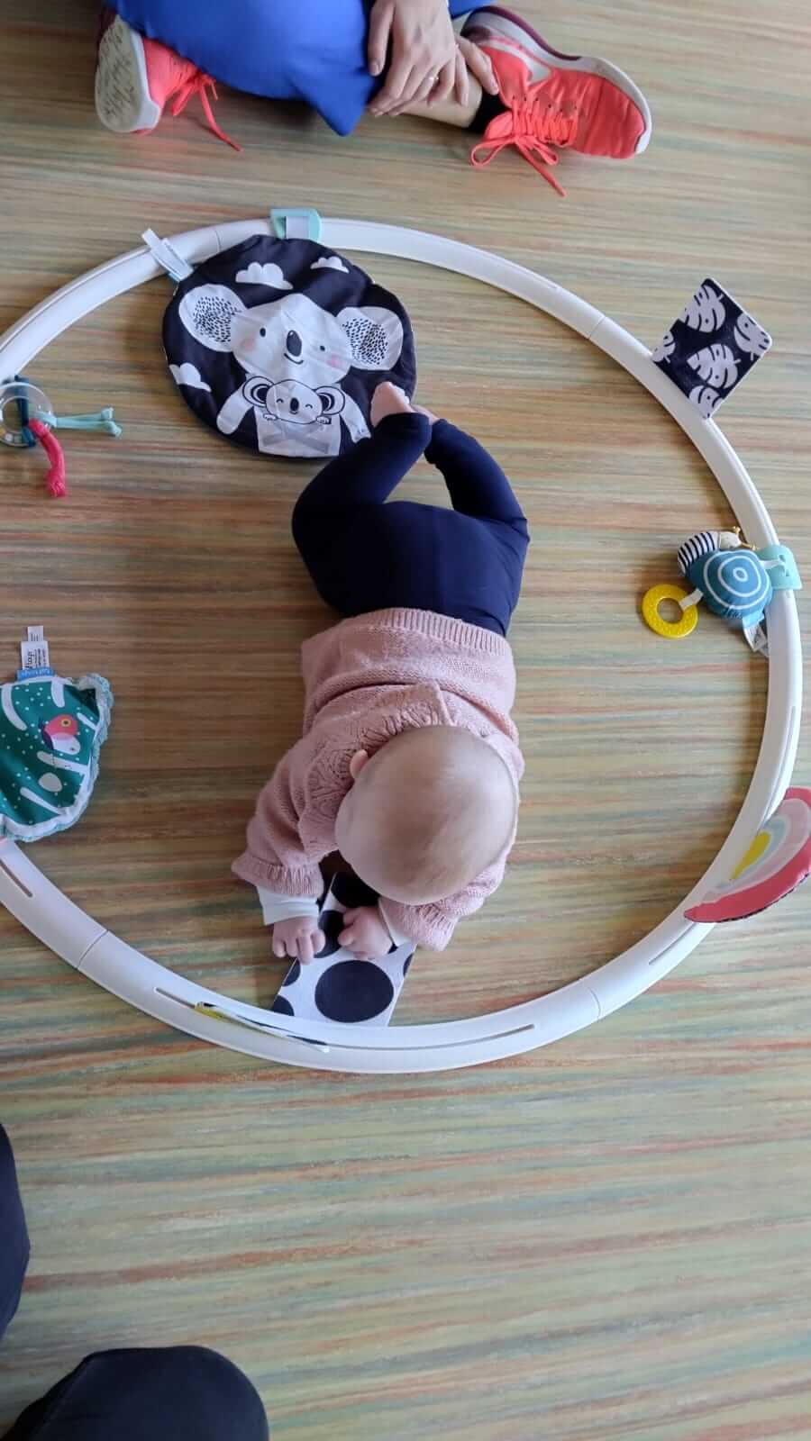 Cerceau 2024 - Activité - GDM Un bébé découvre les matières et les textures au sol dans un cerceau sensoriel